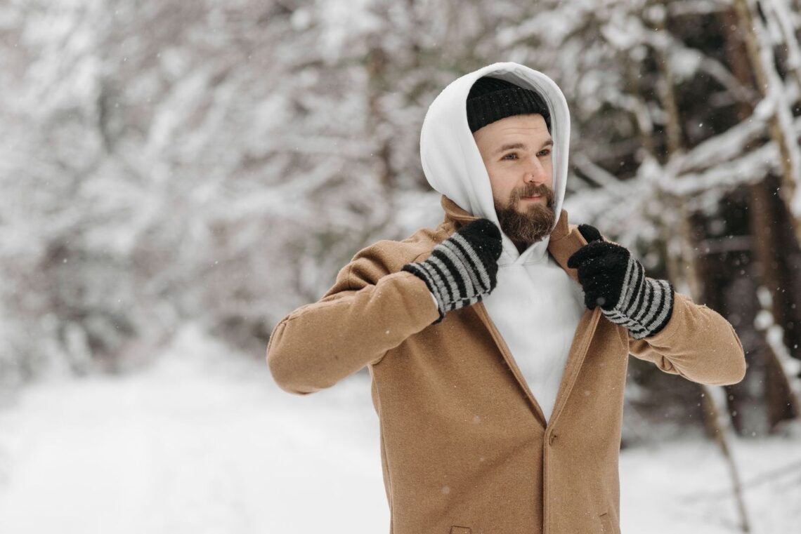 Skäggig man i lager-på-lager-klädsel i snöig skog