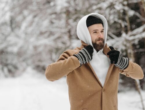 Skäggig man i lager-på-lager-klädsel i snöig skog