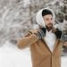 Skäggig man i lager-på-lager-klädsel i snöig skog